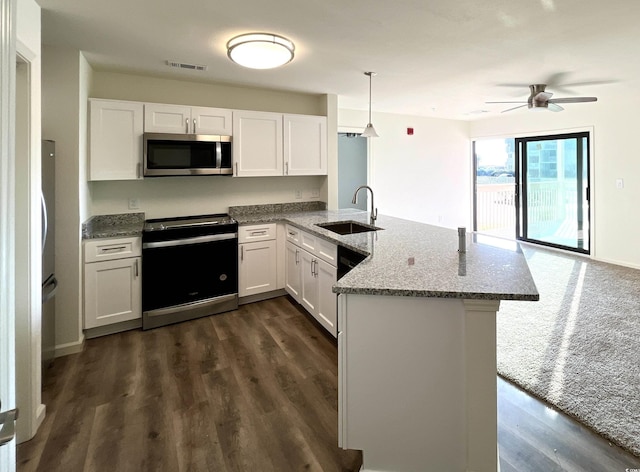 kitchen with stainless steel microwave, a sink, range with electric stovetop, a peninsula, and stone countertops