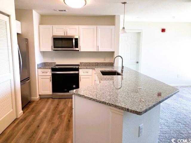 kitchen with sink, white cabinetry, stainless steel appliances, decorative light fixtures, and dark hardwood / wood-style floors