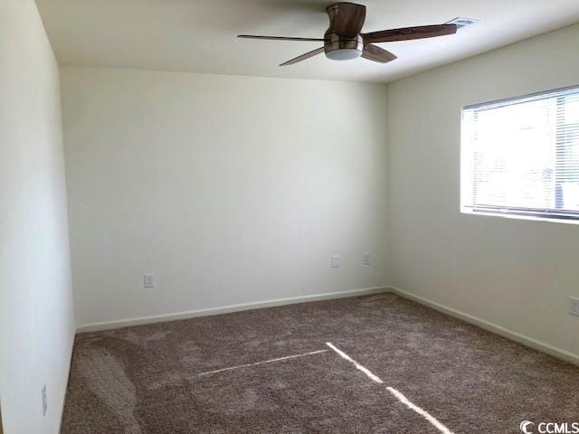 spare room with dark colored carpet and ceiling fan