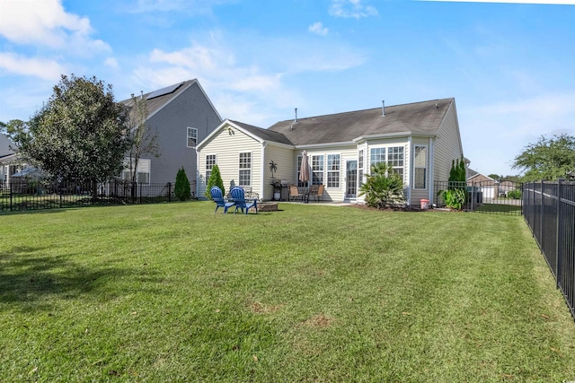 rear view of house featuring a patio, a lawn, and a fire pit