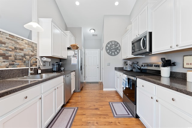 kitchen with white cabinetry, stainless steel appliances, sink, and light wood-type flooring