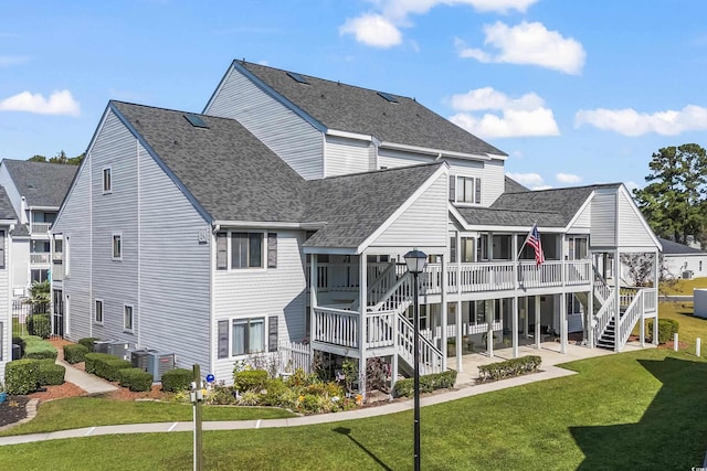 rear view of house featuring a lawn, a sunroom, a deck, and a patio