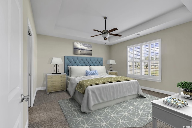 carpeted bedroom with a tray ceiling, baseboards, and ceiling fan