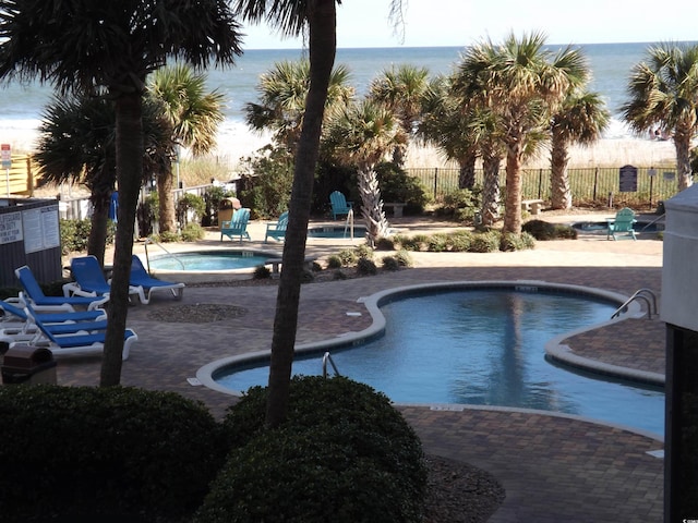 view of swimming pool featuring a patio area, a community hot tub, and a water view