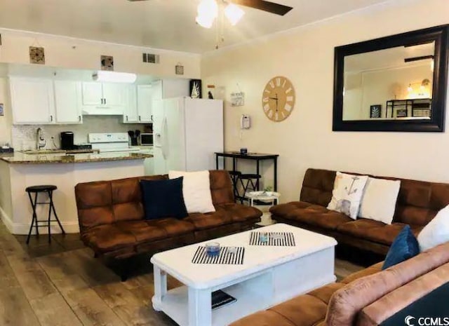 living room with sink, hardwood / wood-style flooring, and ceiling fan