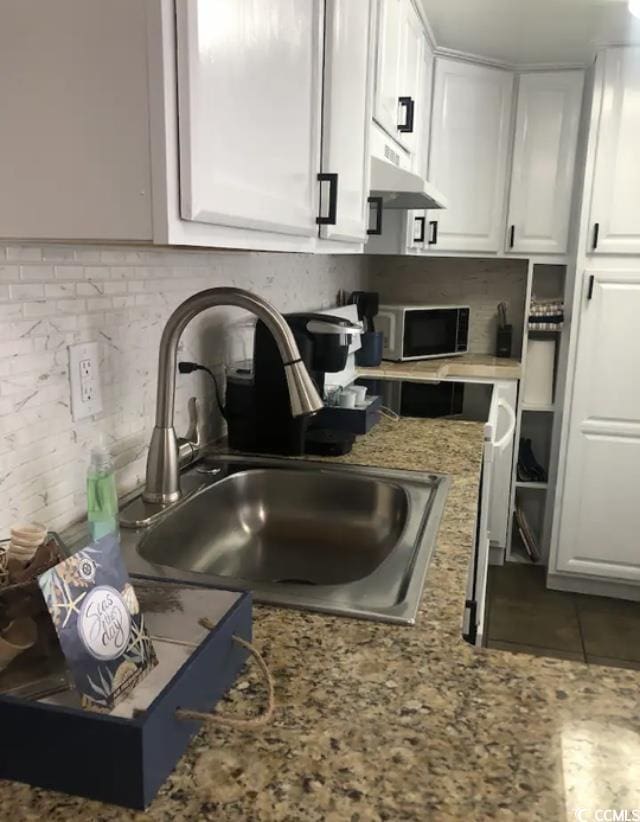 kitchen featuring backsplash, light stone countertops, sink, and white cabinets