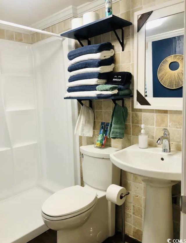 bathroom featuring walk in shower, toilet, tasteful backsplash, tile walls, and ornamental molding