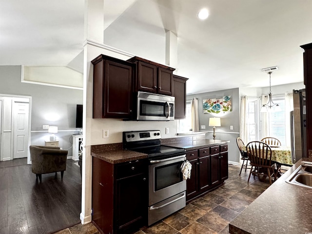 kitchen featuring a healthy amount of sunlight, stainless steel appliances, lofted ceiling, and a notable chandelier