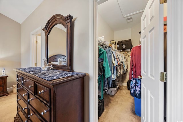 walk in closet with light colored carpet and vaulted ceiling