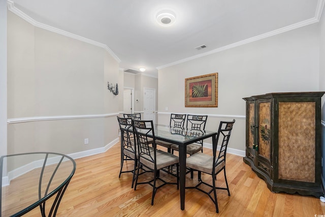 dining area with light hardwood / wood-style flooring and crown molding