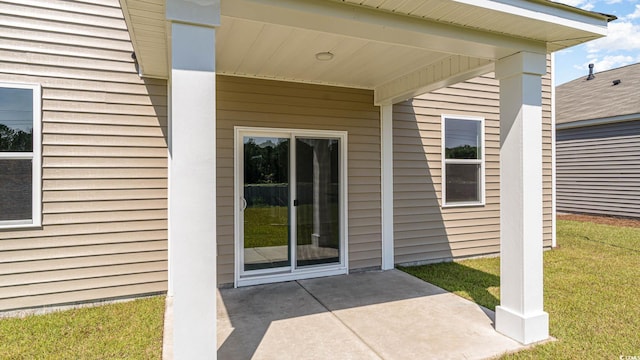 doorway to property featuring a lawn and a patio area