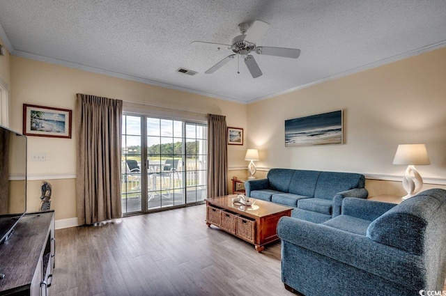 living room with crown molding, ceiling fan, a textured ceiling, and light wood-type flooring