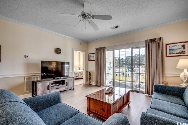 living room with a textured ceiling, light hardwood / wood-style flooring, and ornamental molding