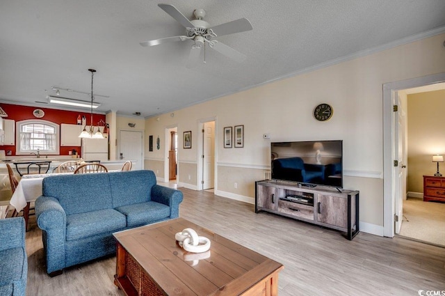 living room featuring light wood-type flooring, ceiling fan, and ornamental molding