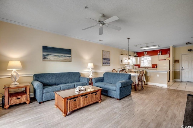 living room with ceiling fan, crown molding, and light hardwood / wood-style floors