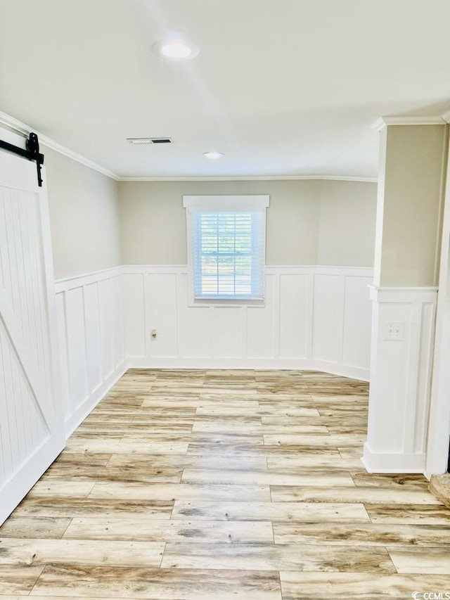 3936 Murrells Inlet Rd, Murrells Inlet, SC 29576 - spare room featuring ornamental molding, light wood finished floors, a barn door, wainscoting, and a decorative wall