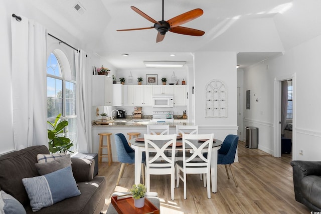 dining space with visible vents, lofted ceiling, ceiling fan, and light wood-style flooring