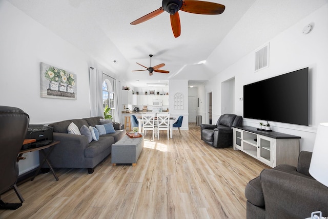 living room with visible vents, light wood-style flooring, ceiling fan, and vaulted ceiling