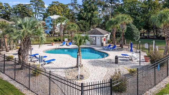 pool featuring a patio area, an outdoor structure, and fence