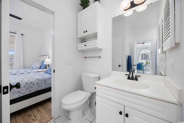 bathroom featuring wood finished floors, toilet, ensuite bath, and vanity