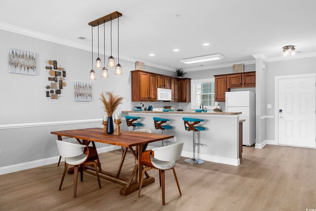 kitchen with ornamental molding, kitchen peninsula, pendant lighting, and white appliances