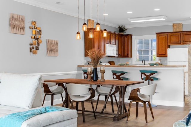 kitchen featuring ornamental molding, white appliances, light wood-type flooring, and pendant lighting