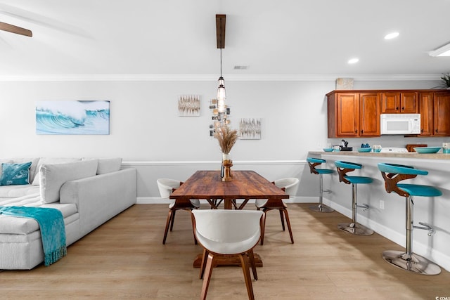 dining space featuring light hardwood / wood-style floors and crown molding