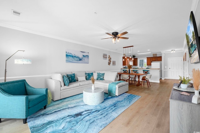 living room featuring ornamental molding, light hardwood / wood-style floors, and ceiling fan