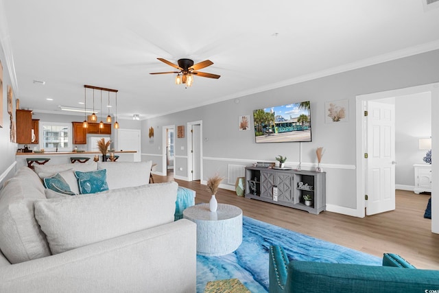 living room with light hardwood / wood-style floors, ornamental molding, and ceiling fan