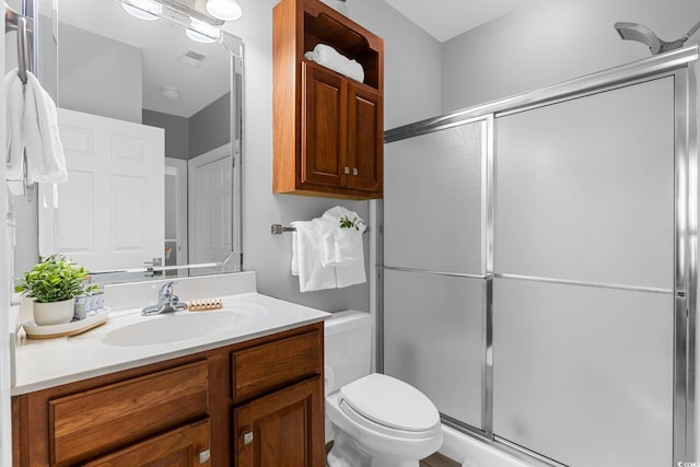 bathroom with vanity, a shower with shower door, and toilet