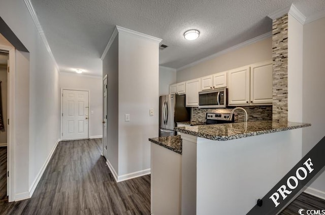 kitchen featuring dark stone counters, a textured ceiling, stainless steel appliances, dark hardwood / wood-style floors, and white cabinetry