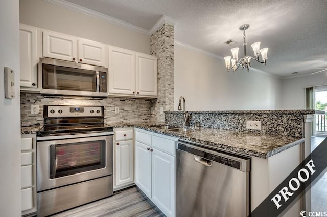 4220 Coquina Harbour Dr Unit B-11, Little River, SC 29566 - kitchen with stainless steel appliances, a peninsula, crown molding, white cabinetry, and a chandelier