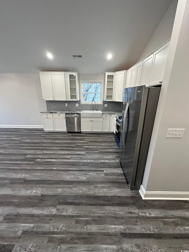 kitchen with appliances with stainless steel finishes, dark hardwood / wood-style flooring, tasteful backsplash, sink, and white cabinets