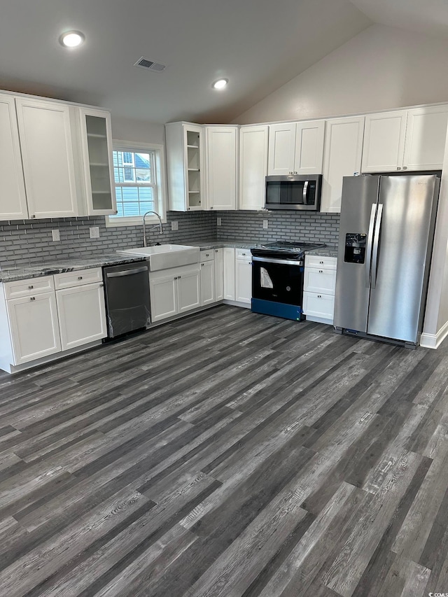 kitchen featuring lofted ceiling, dark wood-type flooring, decorative backsplash, white cabinetry, and stainless steel appliances