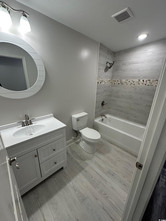 full bathroom featuring vanity, wood-type flooring, tiled shower / bath combo, and toilet