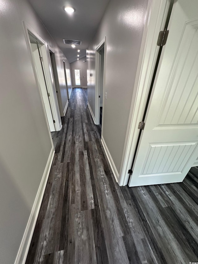 hallway with dark hardwood / wood-style floors and lofted ceiling