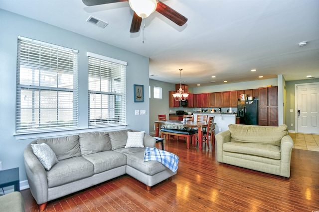 living room with ceiling fan with notable chandelier, a healthy amount of sunlight, and dark hardwood / wood-style flooring