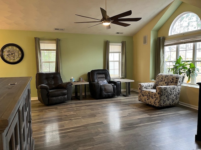 living area with a healthy amount of sunlight, vaulted ceiling, and dark wood-type flooring