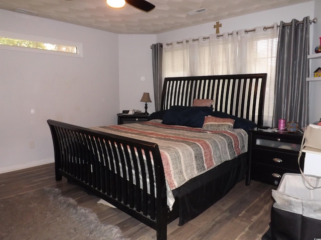 bedroom featuring dark hardwood / wood-style floors, ceiling fan, and multiple windows