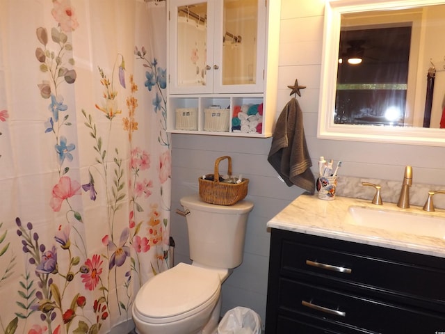 bathroom featuring wood walls, vanity, a shower with shower curtain, and toilet