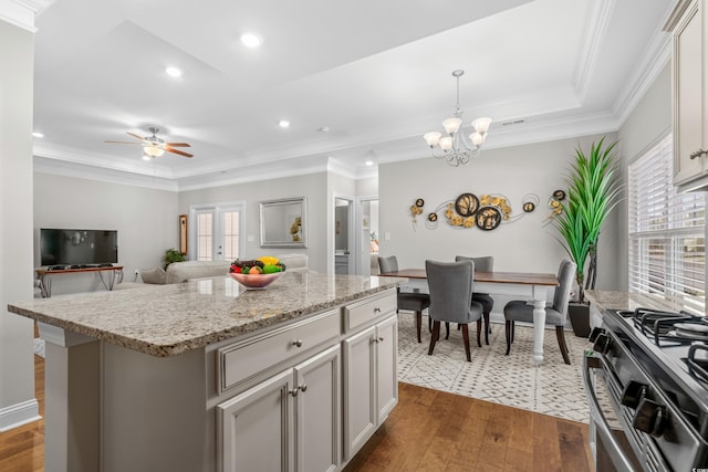 kitchen with stainless steel stove, dark hardwood / wood-style floors, crown molding, decorative light fixtures, and a center island