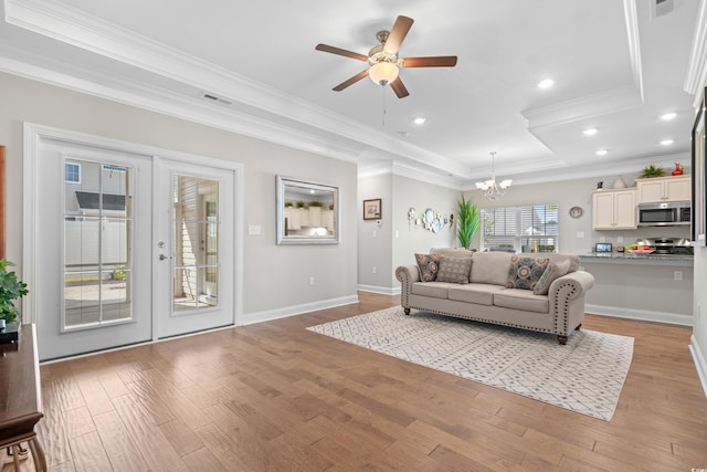 living room featuring french doors, light hardwood / wood-style floors, crown molding, and ceiling fan with notable chandelier