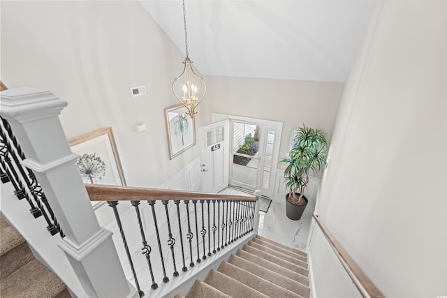 stairs with a notable chandelier, carpet floors, and high vaulted ceiling