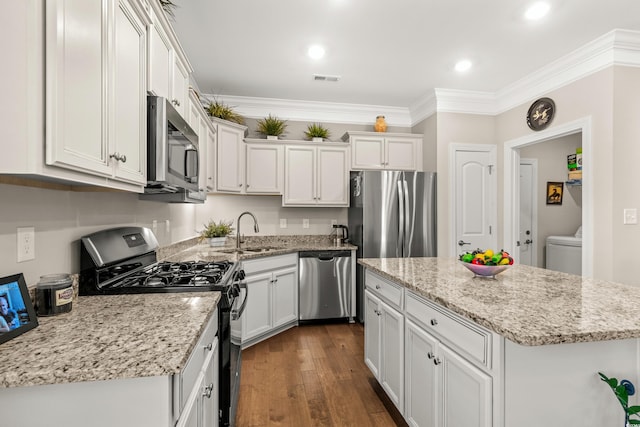 kitchen with stainless steel appliances, crown molding, sink, a center island, and white cabinetry