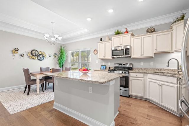 kitchen featuring a center island, appliances with stainless steel finishes, hanging light fixtures, and light hardwood / wood-style floors