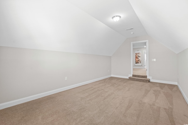 additional living space with light carpet and vaulted ceiling