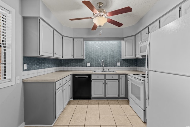 kitchen with gray cabinetry, backsplash, sink, light tile patterned floors, and white appliances