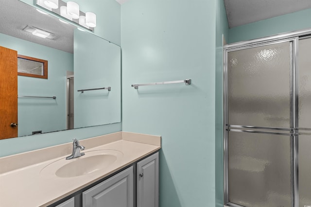 bathroom featuring vanity, a shower with shower door, and a textured ceiling