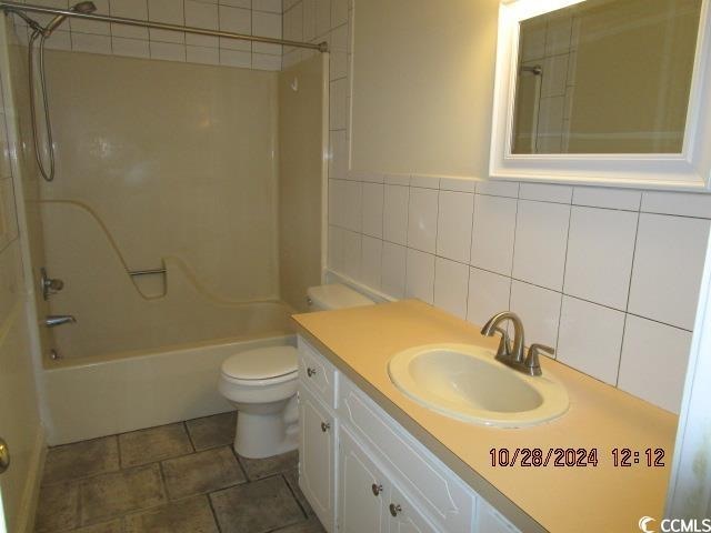 full bathroom with backsplash, vanity, tile walls, toilet, and tiled shower / bath