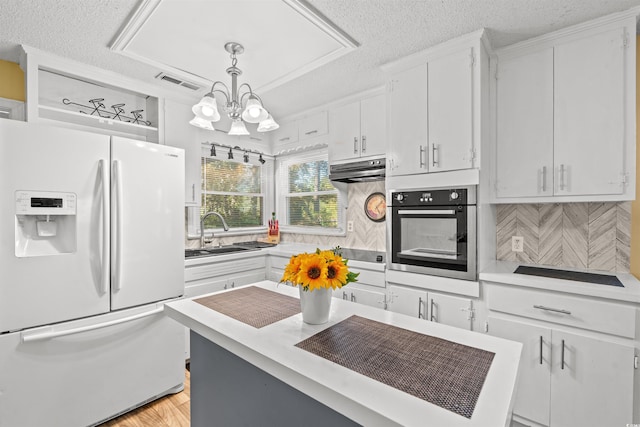 kitchen featuring decorative backsplash, white cabinets, hanging light fixtures, sink, and white refrigerator with ice dispenser